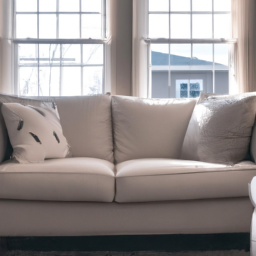 description: an off-white sectional sofa sits in front of two open windows, creating a cozy and inviting atmosphere. the sofa features a slipcover and plush cushions, exuding comfort and relaxation.