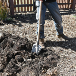 description: an image of a landscaper using a shovel to dig a hole in a garden bed.