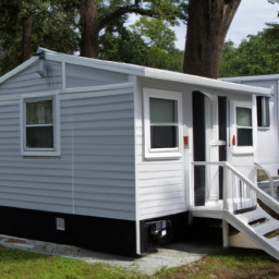 Description: A photo of a newly remodeled mobile home, featuring a freshly painted exterior, new trim, and a porch addition.