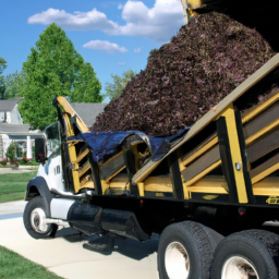 Description: A truck unloading a pile of mulch in a residential driveway.