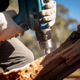 A person wearing protective gear drilling a hole into a piece of timber in order to mount it securely.
